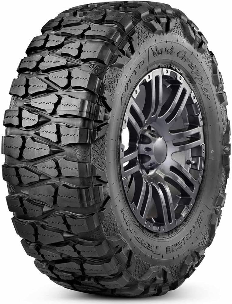 Nitto Mud Grappler extreme terrain tire on a gunmetal alloy wheel, deep tread blocks wrapping over the shoulder into lizard-skin sidewall lugs